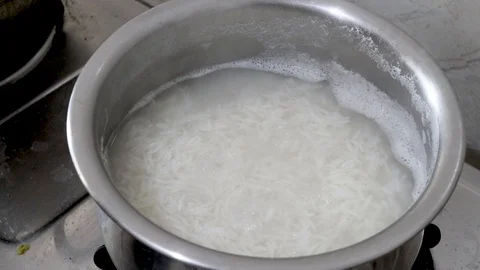 Closeup video of boiling of white rice in water in a steel sauce pan with steam Stock Footage 121698578