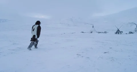 Closeup video of drone in the middle of Arctic walking man through the snowy Stock Footage 112084534