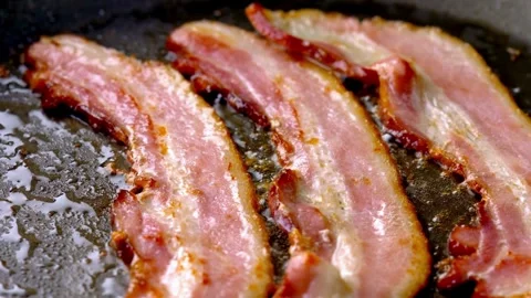 Closeup video of fresh bacon being flipped with spatula on a frying pan. 스톡 동영상 334641582