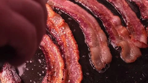 Closeup video of fresh bacon being flipped with spatula on a frying pan. 스톡 동영상 334641674