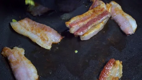 Closeup video of fresh bacon being flipped with spatula on a frying pan. 스톡 동영상 334642015