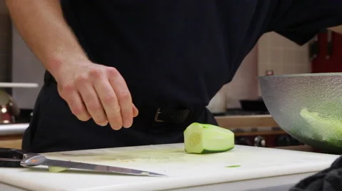 Closeup video of a man slicing a cucumber with a sharp knife in a kitchen. Stock Footage 57400562