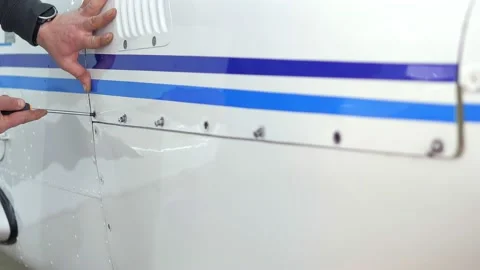 Closeup video of man's hands are taking screwdriver and fixing airplane body in Stock Footage 239095528