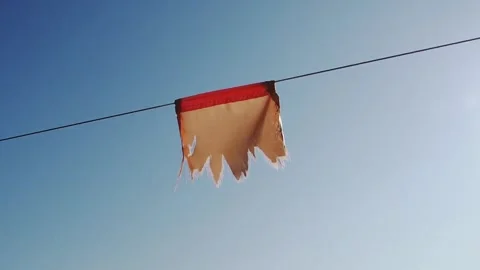 A closeup video of the old torn red protective flag on a rope Stock Footage 241821031