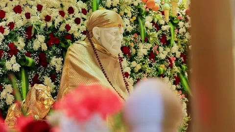 A closeup video of Sai Baba or Sai Ram idol surrounded by floral decoration.. Stock Footage 328011514