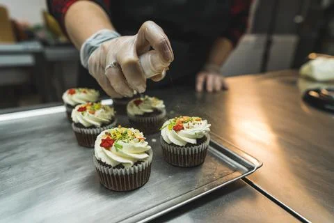 Closeup view of a baker decorating Christmas cupcakes at the bakery Stock Photos