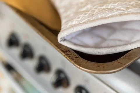 Closeup View Baking Kitchen Gloves on Oven Tray over Retro Style Cooker Stock-Fotos