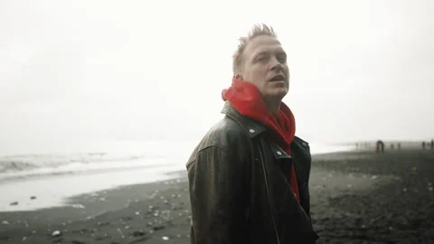 Closeup view of blonde handsome man singing in rain. Reynisfjara beach, Iceland Stock Footage 254116746