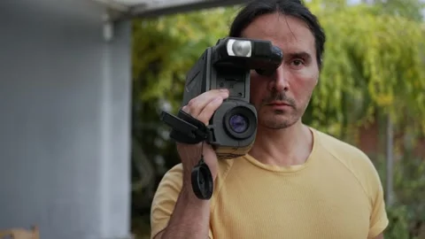 Closeup view of brutal face of a man. Holding vintage black camera for shooting Stock Footage 304683893