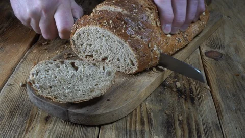 Closeup view. Chef cuts bread into slices on wooden cutting board Video stock 123303525