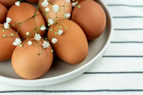 Closeup view of clay plate full of many raw whole brown chicken eggs for co.. Stockfoto's