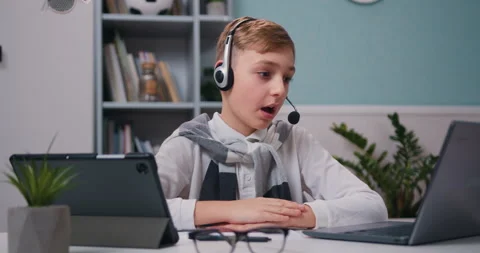 Closeup view of cute boy raises his hand and answers. Kid pupil in headphones Stock Footage 231997927