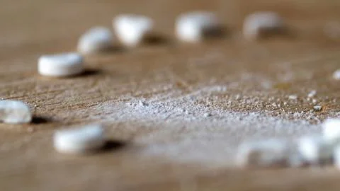 Closeup view cutting white round pill by knife on wooden board Fotos de archivo