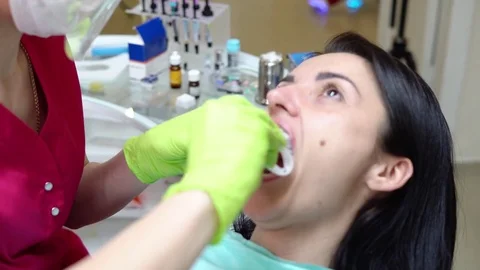 Closeup view of the dentist's hands putting rubber dam in a mouth of a female Stock Footage 74447157