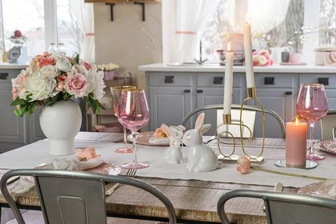 Closeup view of a dreamy table decor with glasses flowers and lit candles. We Stock Photos