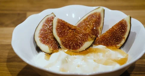 Closeup view dropping pitaschio nuts into a bowl of thyme yogurt and fig piec Stock Footage 94666107