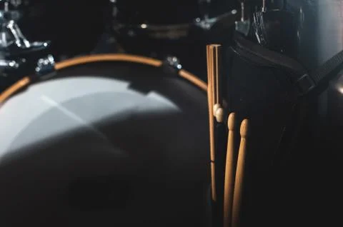 Closeup view of a drum set and Drumsticks in a dark studio. Black drum barrels Stock Photos
