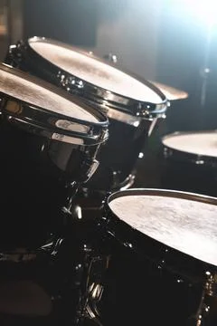 Closeup view of a drum set in a dark studio. Black drum barrels with chrom... Stock Photos