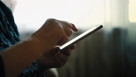 Closeup view on elderly woman uses apps in smartphone. Grandmother is holding Stock Footage 87181294