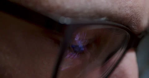 Closeup view of eye behind glasses illuminated by vivid screen reflections Stock Footage 289124665