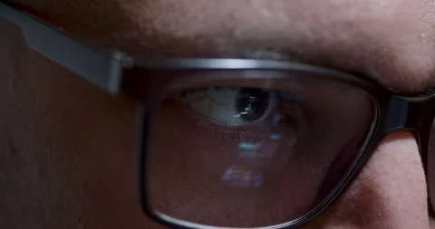 Closeup view of eye behind glasses illuminated by vivid screen reflections 動画素材 289124708