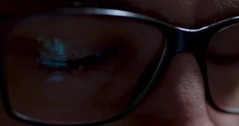 Closeup view of eye behind glasses illuminated by vivid screen reflections 動画素材 289124721
