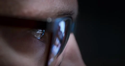 Closeup view of eye behind glasses illuminated by vivid screen reflections Vídeo Stock 289124803