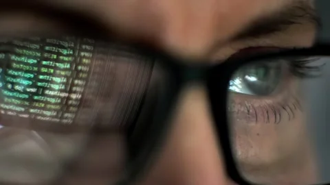A CloseUp view of an Eye Positioned Behind Glasses, Reflecting Complex Data Stock Footage 315340055