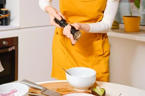 Closeup view of female hands adding ground pepper into salad Foto stock