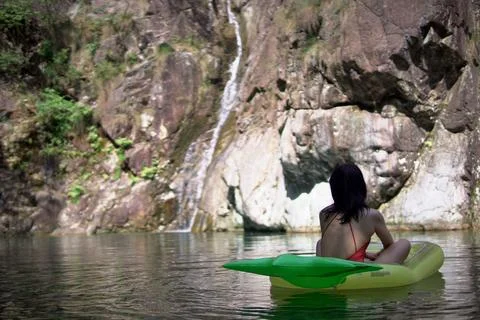 Closeup view of a female on a pool float on a beautiful rocky cliff background Stock Photos