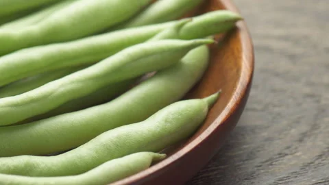 Closeup view of fresh green beans on wooden plate Stock Footage 320332806