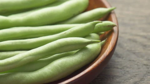 Closeup view of fresh green beans on wooden plate Stock Footage 326615700