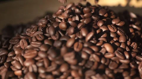 Closeup view of freshly roasted coffee beans falling into a heap, revealing Video stock 276962259