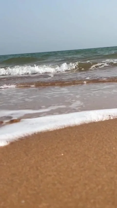 Closeup view of gentle ocean waves washing over the wet sandy beach on a sunny Vídeos de archivo 334163429