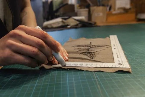A closeup view on the hands of an eco-friendly clothes maker preparing a patch Stock Photos
