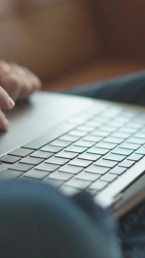 This is a closeup view of hands engaged in typing on a laptop, all while seated Stock Footage 293207191