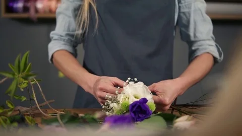 Closeup view of hands of a flower shop assistant tying a bunch of flowers lying Stock Footage 83140165