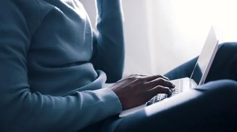 Closeup view of hands of a guy using a laptop placed on his lap and holding Stock Photos