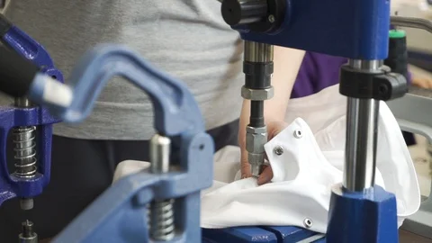 Closeup view of hands of sewer attaching metal round snaps to clothes with help Stock Footage 127976514