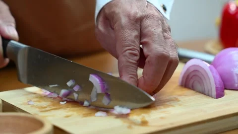 Closeup view of hands slicing red onion on wooden board using a sharp knife.. Stock Footage 312978774