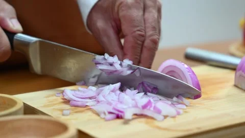 Closeup view of hands slicing red onion on wooden board using a sharp knife.. Stock Footage 312978776