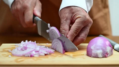 Closeup view of hands slicing red onion on wooden board using a sharp knife.. Video stock 312978818