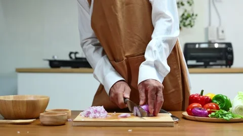 Closeup view of hands slicing red onion on wooden board using a sharp knife.. Stock Footage 312978883