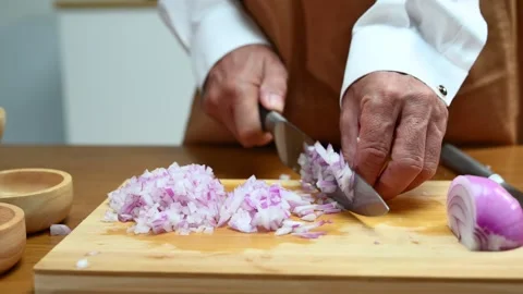 Closeup view of hands slicing red onion on wooden board using a sharp knife.. Video stock 312978887