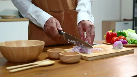 Closeup view of hands slicing red onion on wooden board using a sharp knife.. Video stock 312978939