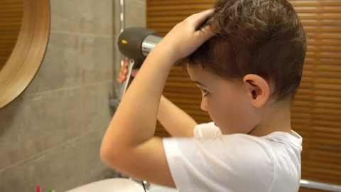 Closeup view of handsome cute young white boy blowing his wet hair by hairdryer Video stock 128780153