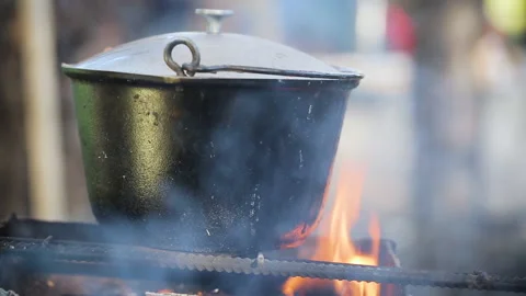 Closeup view of an iron pot boiling on fire place in the woods. Camping cooking. Stockbeeldmateriaal 139784911