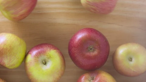 Closeup view of juicy apples rolling on a wooden table Stock Footage 341091292