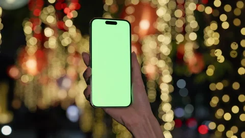 Closeup view of lady hand holds smartphone with chromakey screen by bokeh lights Stock Footage 318967699