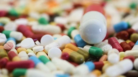 Closeup view of large pill and many small pills spinning Stock Footage 97823018